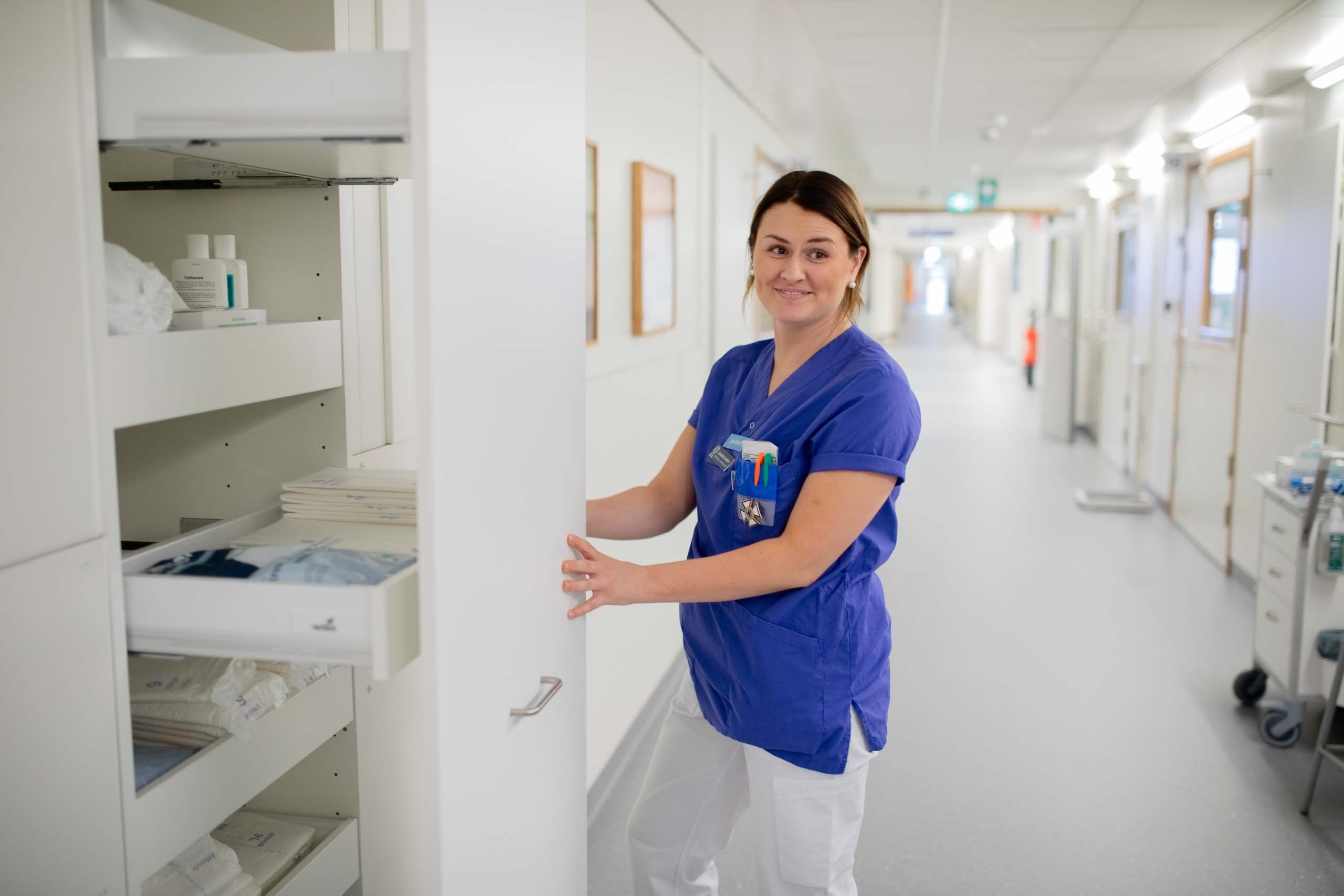 Helsepersonell i korridor på Centralsjukhuset Karlstad i modulsykehus fra Expandia, håndterer medisinsk utstyr i oppbevaringsskap.