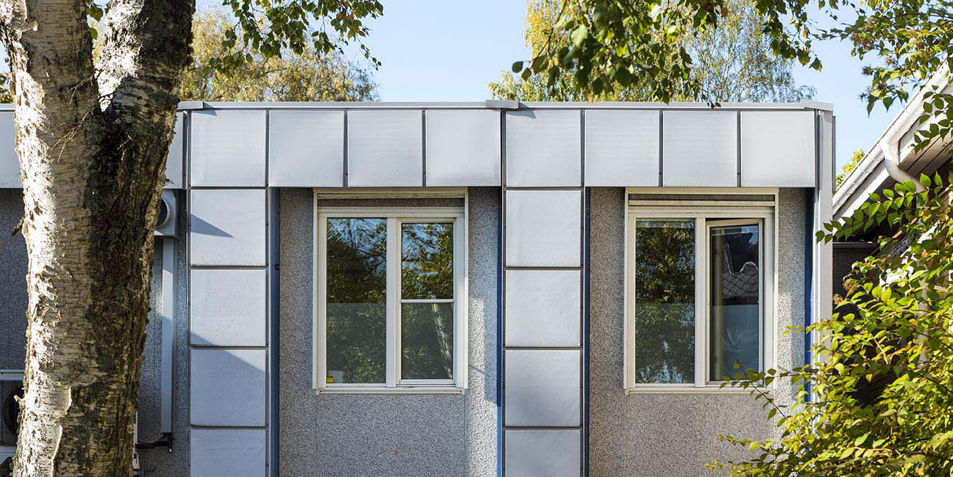 Eksteriør av moduloppført virksomhetslokale fra Expandia med vinduer og fasadepartier, omgitt av trær og grøntområder.