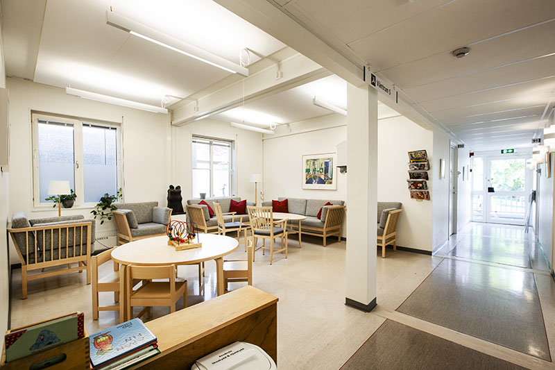 Lyst venteområde i helsesenter oppført med moduler fra Expandia, med sofagrupper, runde bord og korridor mot behandlingsrom.