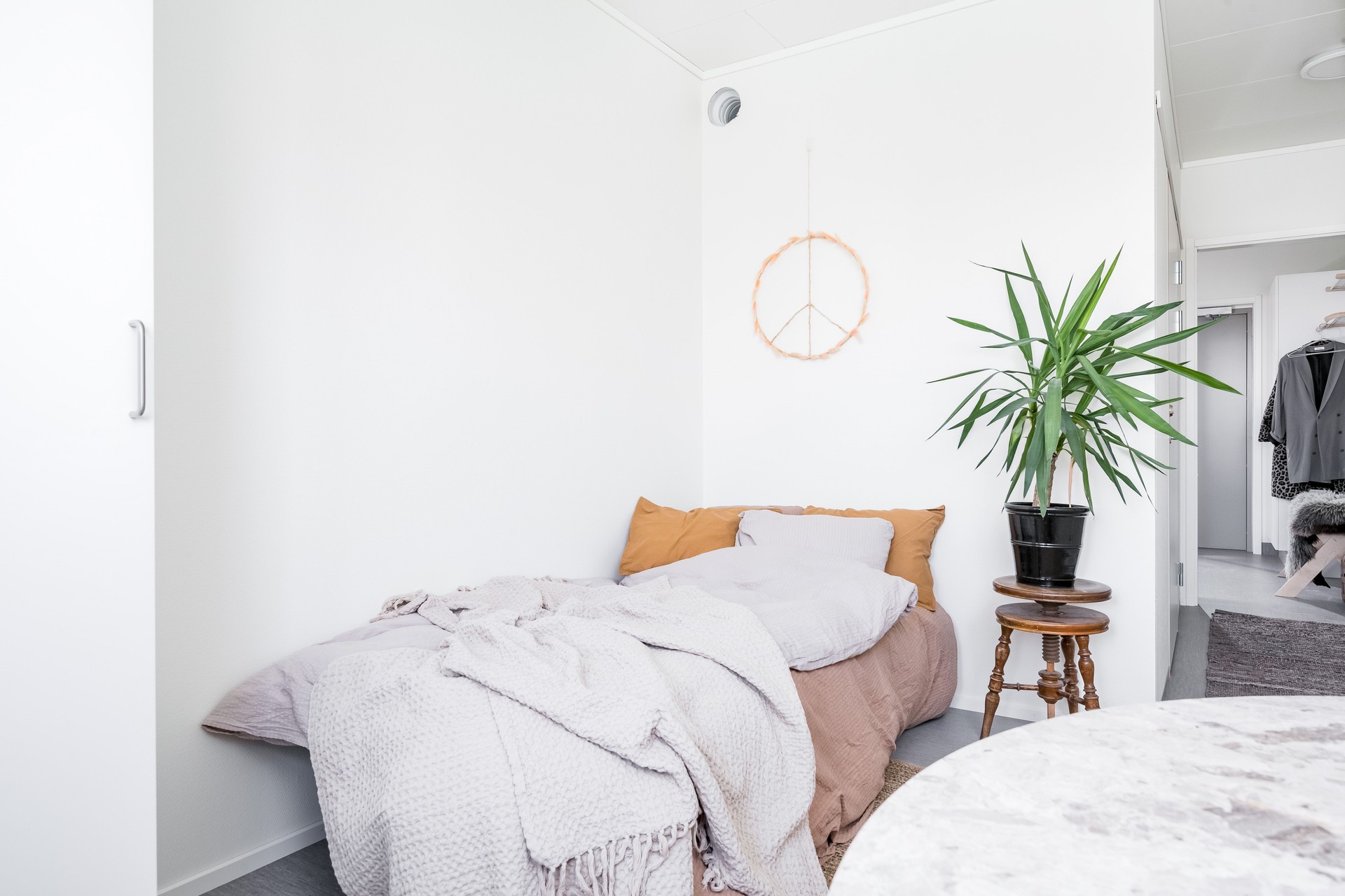 Ljus och harmonisk studentlägenhet i Visby med säng, mjuka textilier och genomtänkt inredning, där gröna växter och personliga detaljer skapar en hemtrevlig känsla i ett modernt och yteffektivt boende, uppfört som modulbaserade studentbostäder från Expandia.