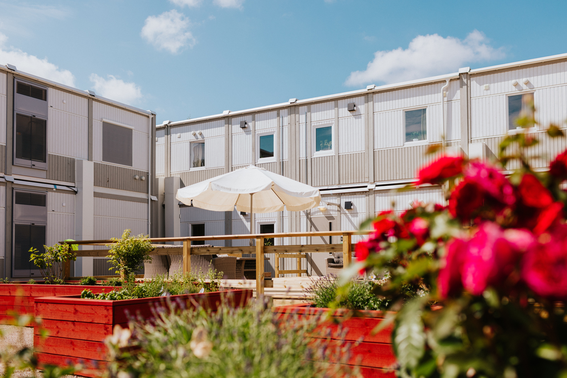 Fin indre gård med blomster og boligmoduler i bakgrunnen