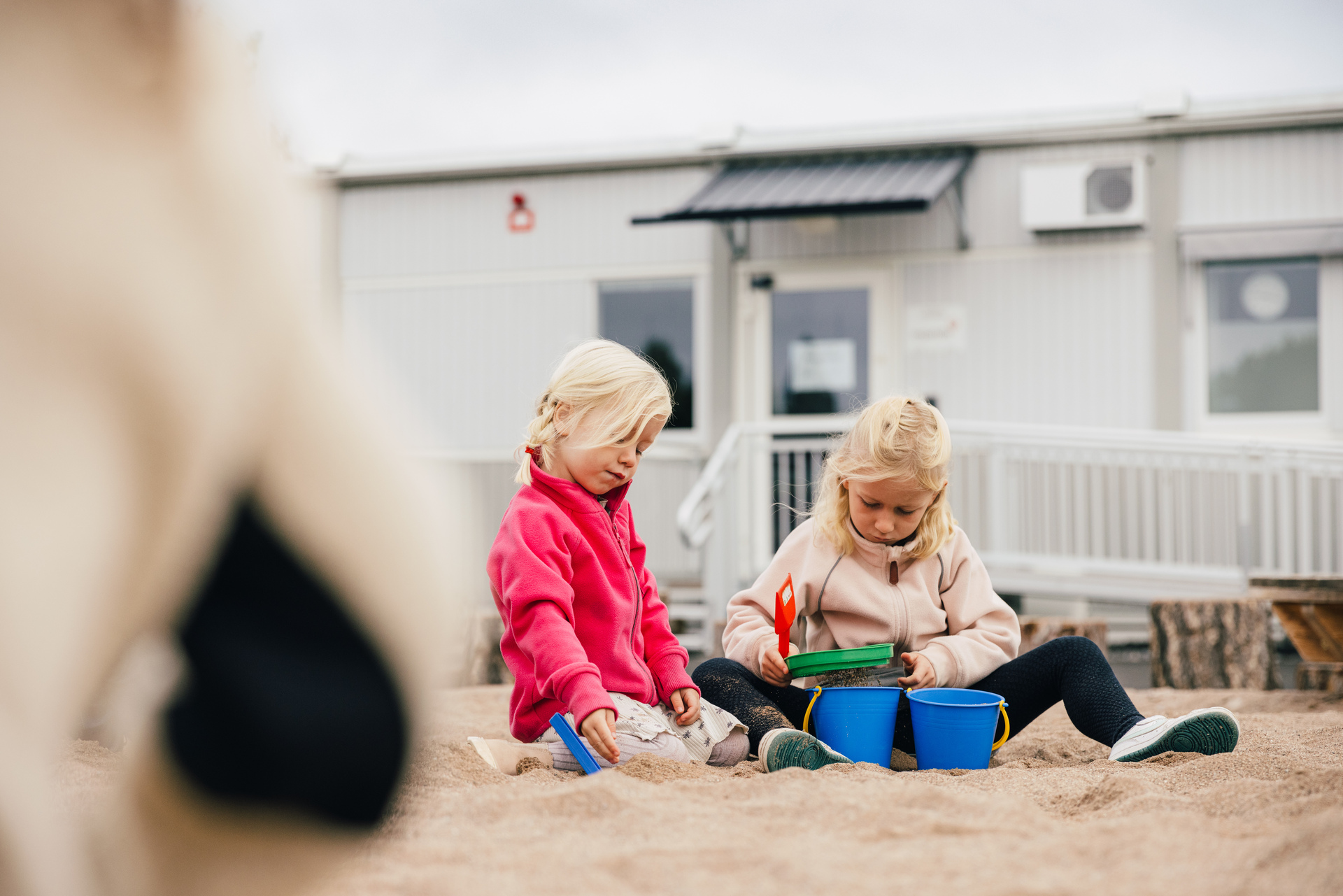 Barn leker i sanden utenfor barnehagemoduler