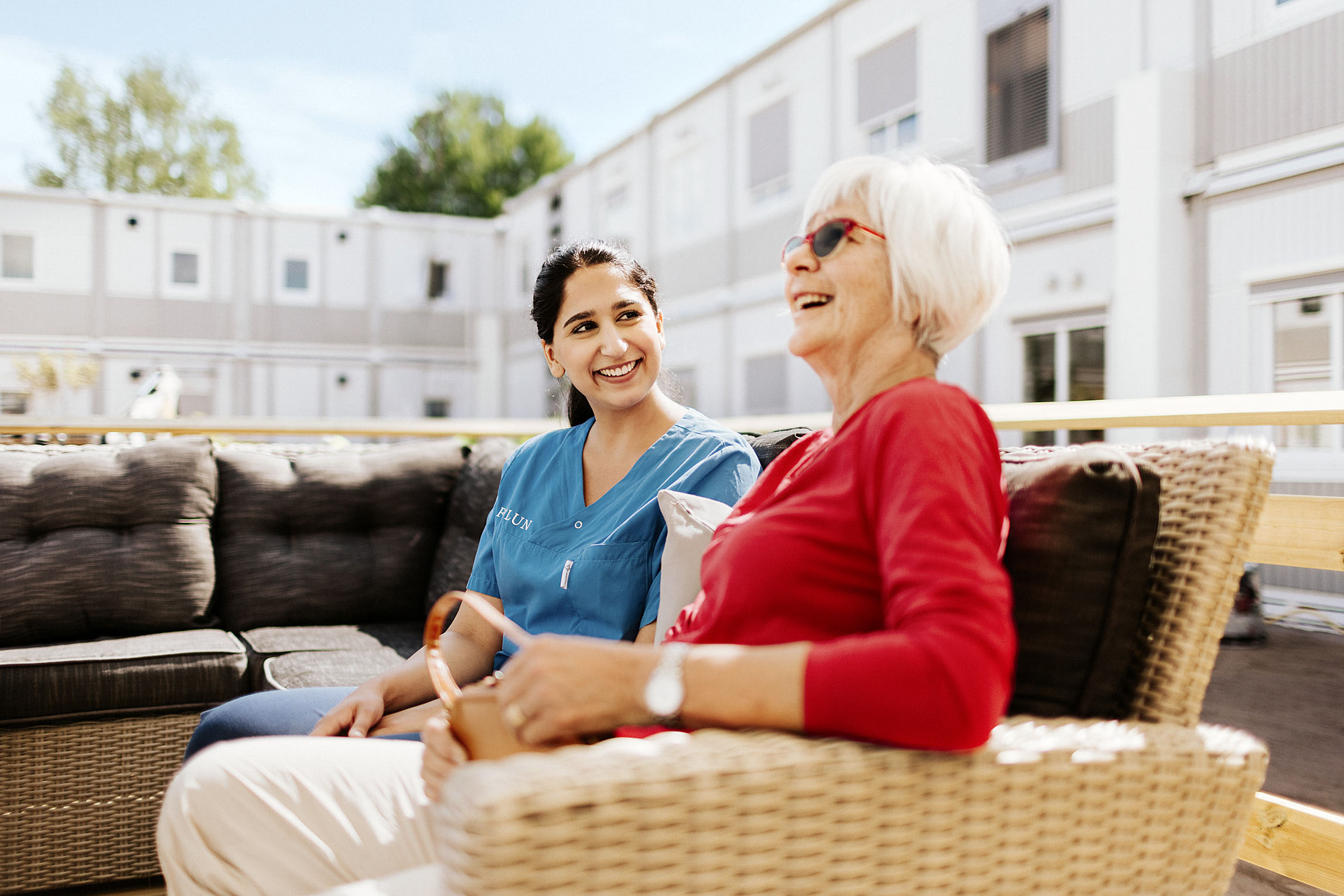 Helsepersonell og eldre kvinne ler utenfor omsorgsmoduler