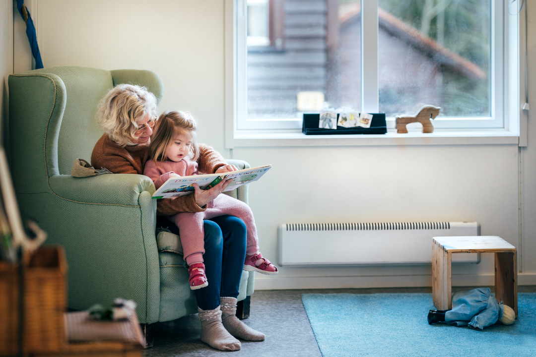 Barn og ansatt som leser sammen i en rolig krok i et lyst barnehagemiljø i modulbygg fra Expandia.