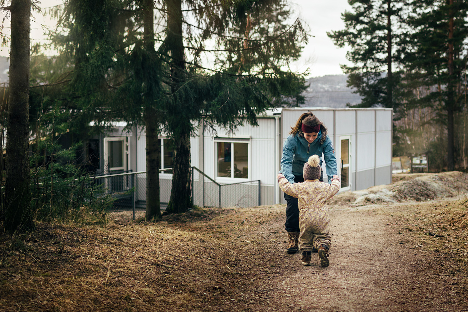 Barn og voksen på tur utenfor Sturlahuset barnehage i Drammen, med modulbygg fra Expandia i naturskjønne omgivelser.